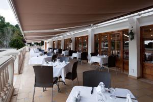 a restaurant with white tables and chairs on a patio at Minura Cala Galdana & Apartamentos d'Aljandar in Cala Galdana