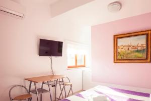 1 dormitorio con cama, mesa y TV en Mon Perin Castrum - Rooms Dado en Bale