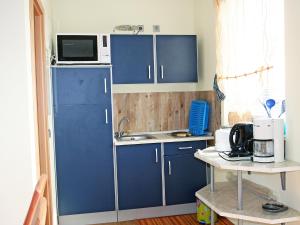 a kitchen with blue cabinets and a microwave at Holiday Home Goetheallee by Interhome in Krakow am See