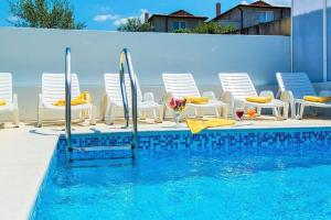 a swimming pool with chairs and a table and a swimming pool at Villa Sanja in Plovanija