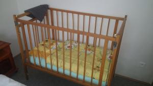 a crib with a yellow bedspread on it at Zelený dům in Svoboda nad Úpou