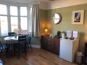 a kitchen with a table and a refrigerator and a dining room at Burlington House Guest House in Hunstanton