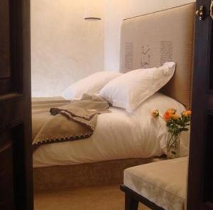 Una cama con almohadas blancas y un jarrón con flores. en Riad Dar Selen, en Marrakech