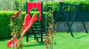 un parque infantil con un asiento rojo y un columpio en Residence Corte Delle Rose, en Garda