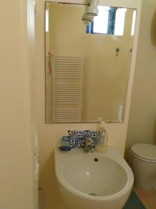 a bathroom with a sink and a mirror and a toilet at Alicudi Giardino dei Carrubi- al gradino 365 in Alicudi