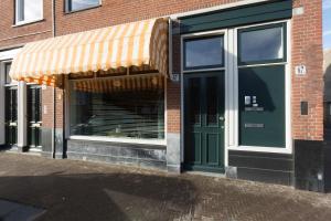 een winkel met een groene deur op een bakstenen gebouw bij VeenkadeBnB in Den Haag
