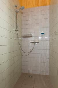 een douche in een badkamer met witte tegels bij VeenkadeBnB in Den Haag