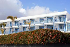 un bâtiment blanc avec des palmiers et des fleurs dans l'établissement Aparthotel Costa Volcán & Spa, à Puerto del Carmen