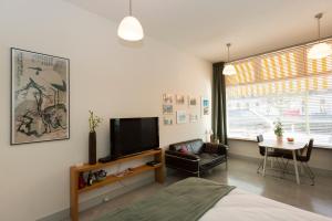 a living room with a bed and a tv and a table at VeenkadeBnB in The Hague