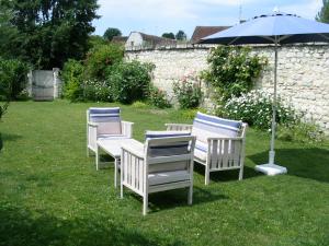 a group of chairs sitting in the grass with an umbrella at Chambres d'Hôtes Les Bords du Cher in Saint-Aignan