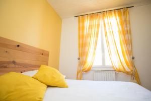 a bedroom with a bed with yellow pillows and a window at La Cauquière By L'Epicurienne in Le Beausset