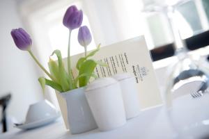 a white vase with purple flowers in it on a counter at The Bridge House in Ross on Wye