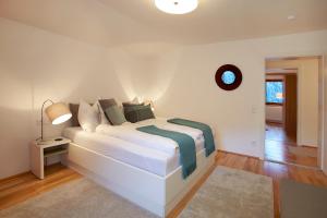 ein weißes Bett in einem weißen Zimmer mit einer Lampe in der Unterkunft Ferienhaus Schmidl in Heiligenblut