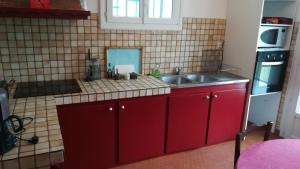 una cocina con armarios rojos y fregadero en Entre mer montagne Béarn et Pays Basque, en Orthez