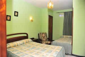 Un dormitorio con 2 camas y una silla. en Pensión Ariz en Basauri