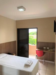 Schlafzimmer mit einem Bett, einem Tisch und einem Fenster in der Unterkunft Hotel 2 Gauchos in Naviraí