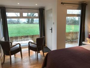 a bedroom with a bed and chairs and a large window at TOR Rooms in Canterbury