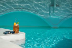 a pineapple and sunglasses sitting next to a swimming pool at On The Rocks - Small Luxury Hotels of the World in Imerovigli