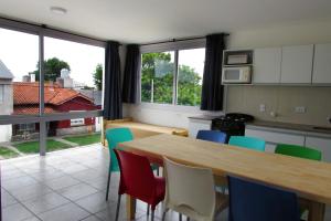 cocina con mesa de madera, sillas y ventanas en PH Mogotes en Mar del Plata