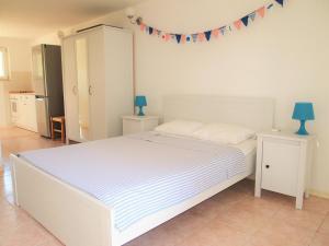 a bedroom with a white bed with blue lamps and flags on the wall at Studio Apartment Branko in Novalja