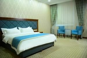 a hotel room with a bed and two blue chairs at Hotel Arai Plaza in Taraz +27 photos