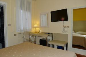 a hotel room with a bed, desk and television at Hotel Centrale Byron in Ravenna