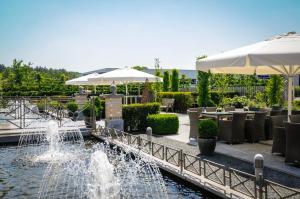 a fountain in a park with tables and umbrellas at De Vesten Comfort Lodge in Laakdal
