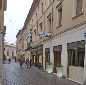 eine Kopfsteinpflasterstraße mit Leuten, die die Straße entlang gehen in der Unterkunft Hotel Centrale Byron in Ravenna