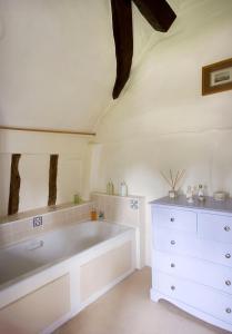 een witte badkamer met een bad en een dressoir bij The Old Manor House in Halford