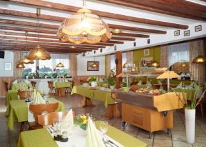 a restaurant with green tables and chairs and a buffet at Hotel Garni Assion in Birgel