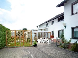 eine Terrasse mit einem Zaun, einem Tisch und Stühlen in der Unterkunft Hotel Restaurant Assion in Birgel