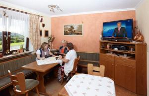 eine Gruppe von Personen, die an einem Tisch in einem Zimmer sitzen in der Unterkunft Hotel Garni Assion in Birgel