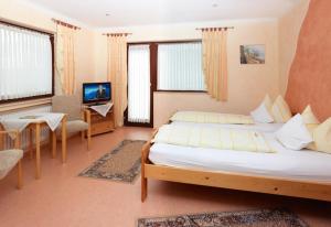 a bedroom with two beds and a table and a television at Hotel Garni Assion in Birgel