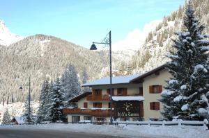 a house with a ski lodge and a mountain range at IHR Hotel Villa Emma in Canazei