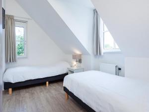 two beds in a room with two windows at Holiday Home de Witte Raaf-1 by Interhome in Noordwijkerhout