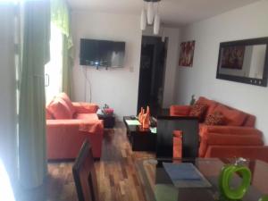 sala de estar con sofás naranjas y TV en Mi casa es su casa, en Lima