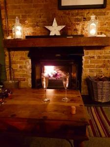 two wine glasses on a wooden table in front of a fireplace at Brooklyn lodge in Margate