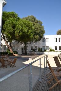une terrasse avec des chaises et un arbre en face d'un bâtiment dans l'établissement Auberge de Jeunesse, à La Rochelle