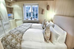 Un dormitorio con una cama blanca con almohadas y una ventana en Ferienwohnung Liiger Wal, en Morsum