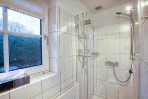 a white bathroom with a shower and a window at Ferienhaus Horstweg 5 in Tinnum