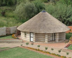 a small building with a thatched roof at Black Swan Guesthouse in Maseru