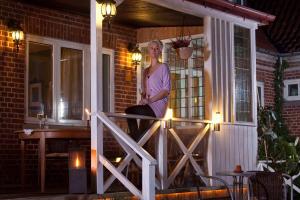 una mujer sentada en el porche delantero de una casa en Hotel Lolland, en Nørreballe