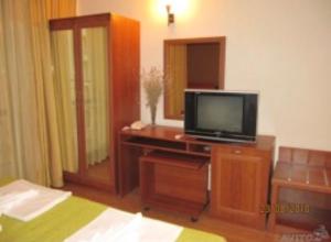 a bedroom with a tv on a wooden dresser at Hotel AVALON in Nesebar