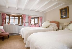 a bedroom with two beds and a chair and windows at The Old Manor House in Halford