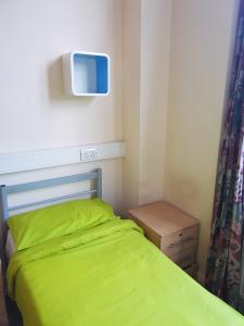 a bedroom with a green bed and a tv on the wall at Belsize House (Belsize Park) in London