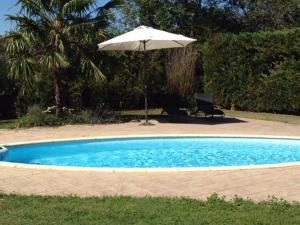 a pool with an umbrella and a chair and a table with an umbrella at Les Glycines in Saint-Gaudens