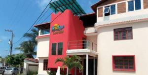 a red building with a sign on the side of it at Pousada Recifes de Corais in Porto De Galinhas