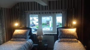 two beds in a room with a window at Marie's Bed and Breakfast in Coolock