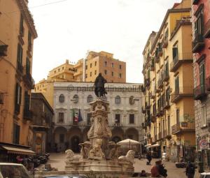 a fountain in the middle of a city with buildings at Lùre Holiday Napoli in Naples