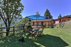 a table and chairs with a blue umbrella in the grass at Agriturismo Le Scope in Molazzana